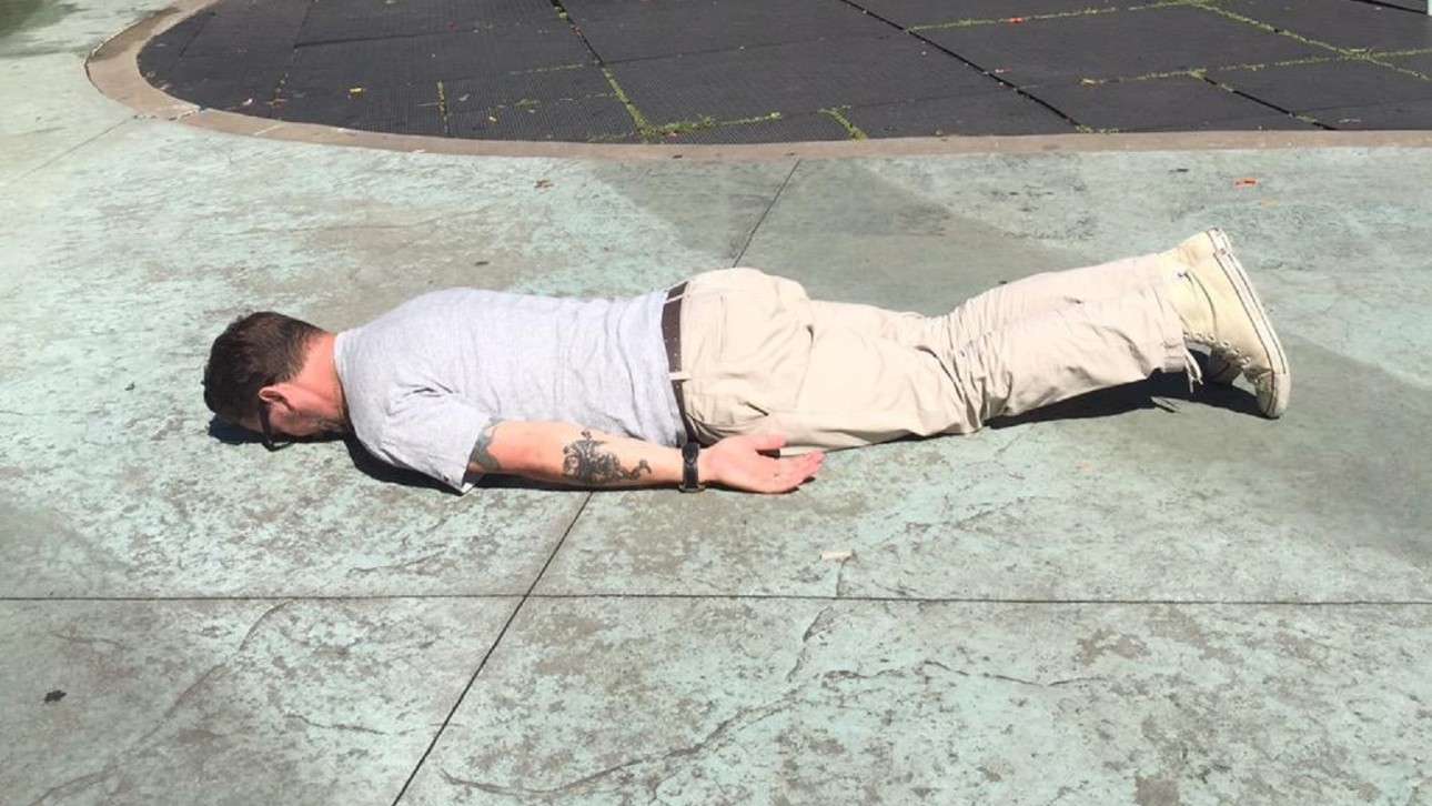 Лежит над человеком. Человек лежит на тротуаре.